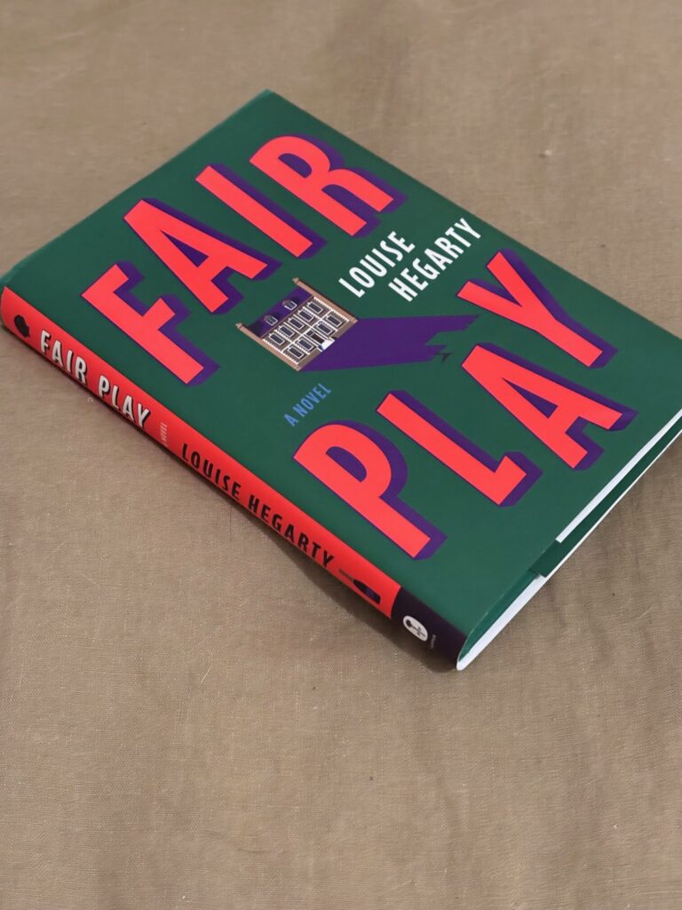 The book "Fair Play" by Louise Hegarty is shown on a green duvet.