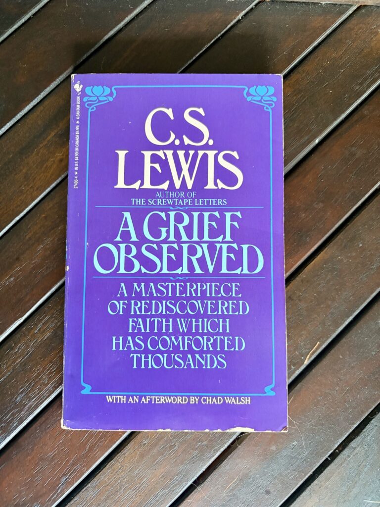 A worn trade paper edition of C.S. Lewis' "A Grief Observed" lies on a walnut-colored wood coffee table
